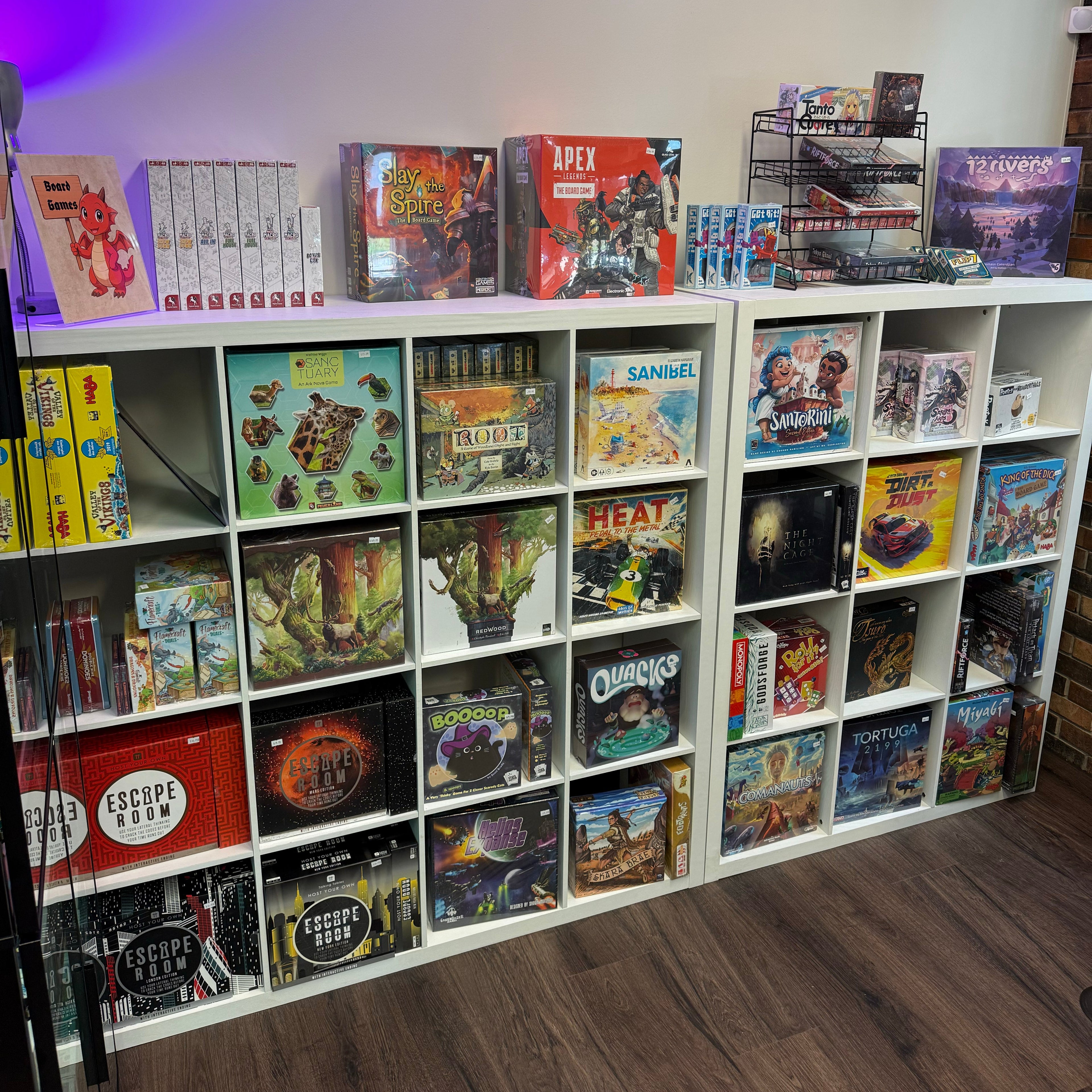 Shelves filled with various board games in a room with purple lighting.